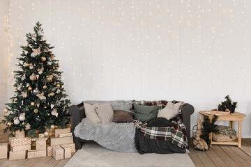 interior design in a light Scandinavian style with a soft sofa with blankets and pillows, next to a Christmas tree with decorations and garlands