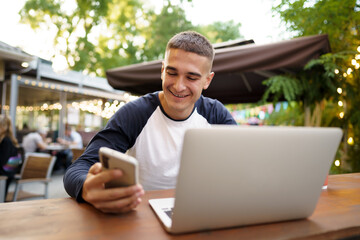 Young man using smartphone while sitting at outdoor cafe