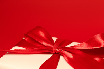 Gift box wrapped in white paper with a red bow. Place for text.Selective focus