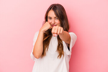 Young caucasian woman isolated on pink background throwing a punch, anger, fighting due to an argument, boxing.