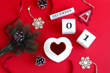 Calendar for December 1: the name of the month in English, cubes with numbers 0 and 1, a cup of tea in the shape of a heart, a fir branch, cones, Christmas decor on a red background, top view