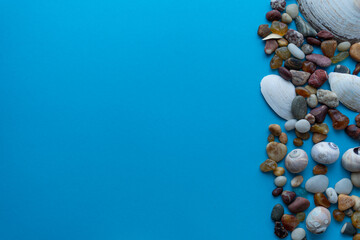 Flat lay composition sea pebbles and seashells on a blue background. space for text