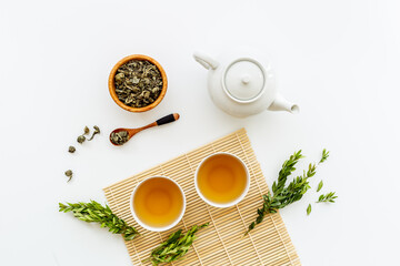 Ceramic white teapot and black tea in two cups, top view