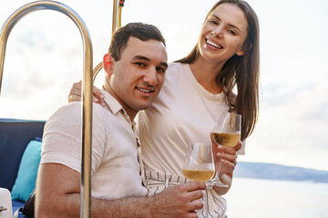 Young loving couple sitting on the yacht deck and drinking wine