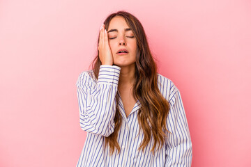 Young caucasian woman isolated on pink background tired and very sleepy keeping hand on head.
