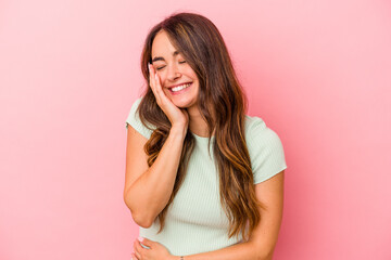 Fototapeta premium Young caucasian woman isolated on pink background laughs happily and has fun keeping hands on stomach.