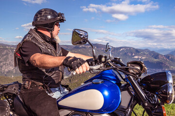 guy riding a retro cruiser motorcycle on mountain road in South tyrol enjoying the beautiful view - obrazy, fototapety, plakaty