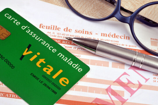 Carte d'assurance maladie française posée sur une feuille de soins de travail à côté d'un stylo et de lunettes