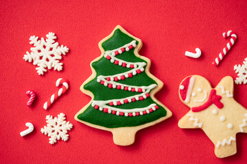 Naklejka na ściany i meble Decorated Christmas gingerbread cookies on red table background.