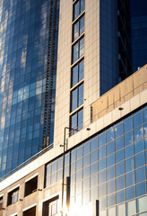 Fototapeta premium Cityscape detail. Sunlight on glass building walls reflectings clouds