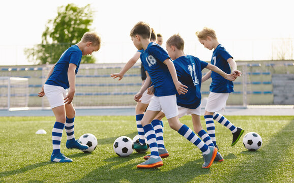 Football Team in Blue Soccer Uniforms on Training Class With Balls. Kids Kicking Balls on Grass Venue. Soccer Class For School Kids