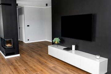 Black matte TV wall in the living room with a standing TV set on a white hanging cabinet.
