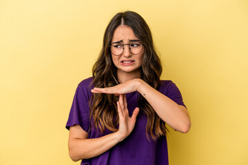 Young caucasian woman isolated on yellow background showing a timeout gesture.
