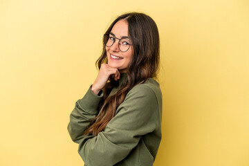 Young caucasian woman isolated on yellow background smiling happy and confident, touching chin with hand.