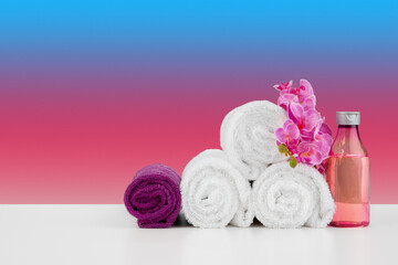 Stack of white towels and bottles of skincare on white table