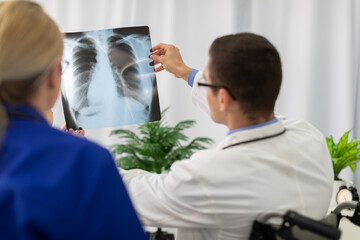 A doctor and nurse look at a photograph of a patient's lungs.