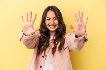 Young caucasian woman isolated on yellow background showing number ten with hands.