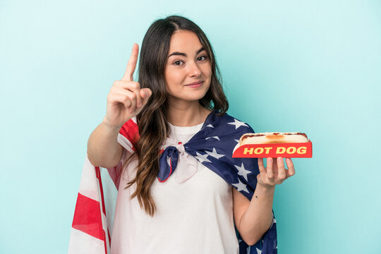 Young Caucasian Woman Holding A Hot Dog Isolated On Blue Background