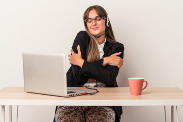 Young caucasian woman doing telecommuting isolated on white background hugs, smiling carefree and...