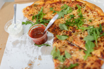 Unfinished pizza with arugula leaves at a college party.