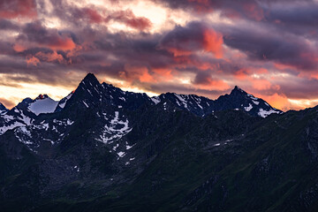 Fototapeta na wymiar Orange clouds over the mountain ridge in austrian Stubai Alps. 