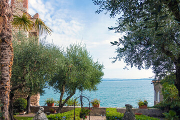 Blick über einen Garten auf den Gardasee in Sirmione in Italien