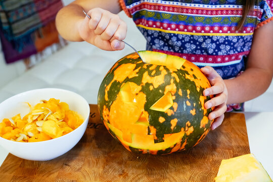 Femmele child carving a pumpkin at Halloween sit at home lantern o jack