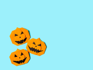 Halloween concept. Paper origami pumpkin on bright blue background. Simple idea for halloween - easy made paper pumpkins on light blue color background. Copy space for text.