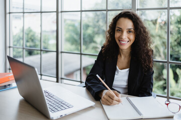 Young business woman write a notebook with laptop on her desk.
