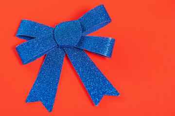 Christmas composition blue glitter bow on a red background. Christmas card, copy space.