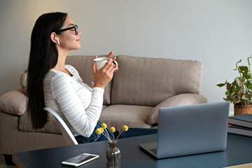 Young beautiful woman with blissful facial expression taking a break at the office to meditate. Brunette female relaxing on a chair by her workspace at lunch time. Close up, copy space, background