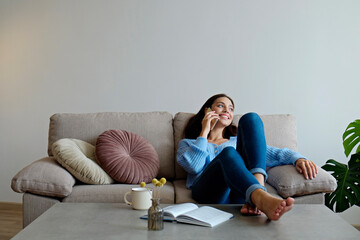 Portrait of young beautiful brunette woman talking on the phone and smiling. Joyful female model having fun phone call. Background, copy space, close up.