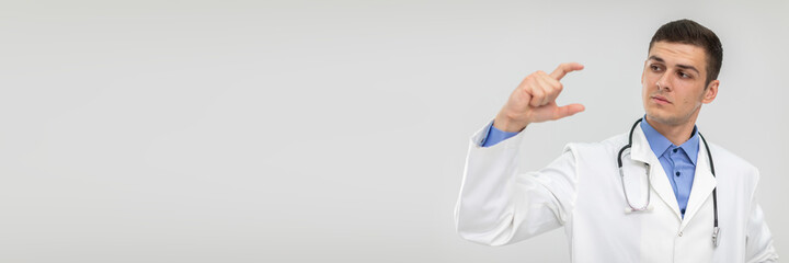 A doctor holds a blank space in two fingers to promote a new product. Panoramic view.