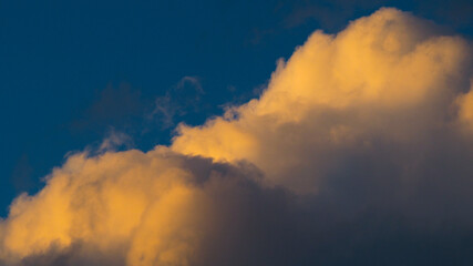 Fototapeta na wymiar Zoom sur un cumulus illuminé par une lumière orangée, pendant le coucher du soleil
