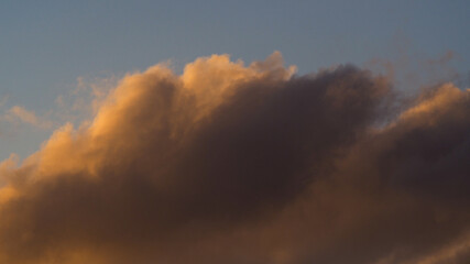 Zoom sur un cumulus illuminé par une lumière orangée, pendant le coucher du soleil