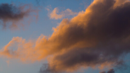Zoom sur un cumulus illuminé par une lumière orangée, pendant le coucher du soleil
