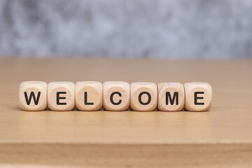 Wooden cube with the word WELCOME on the wooden floor.