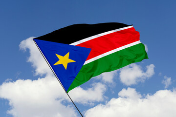 South Sudan flag isolated on the blue sky background. close up waving flag of South Sudan. flag symbols of South Sudan. Concept of South Sudan.