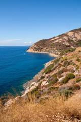 Fototapeta na wymiar Panoramic view over rocky beach of little village Chiessi and coastal road in autumn at western Elba Island, Italy