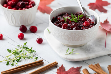 Close up of a bowl of fresh cranberry sauce and frozen cranberries in behind.