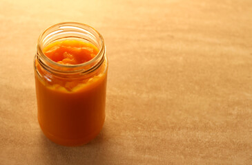 children's pumpkin puree in a glass jar on a beige background