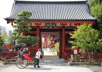 浅草で、人力車にのった観光客が、お寺の門前を眺めている - obrazy, fototapety, plakaty