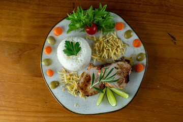 Decorated, delicious and colorful dish served with rice, salad, French fries and roast beef, decorated with fine herbs, top view, wooden background