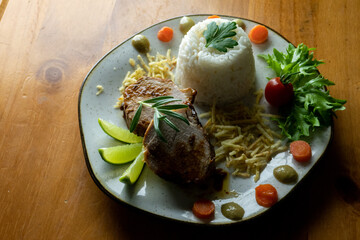 Decorated, delicious and colorful dish served with rice, salad, French fries and roast beef, decorated with fine herbs, photo seen from above