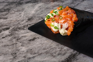 Japanese temaki with salmon, cream cheese and chives, made in Brazilian style on a marble table and on a black surface with copy space