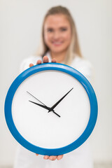 The doctor holds a wall clock in her hands and reminds you that it's time to treat.