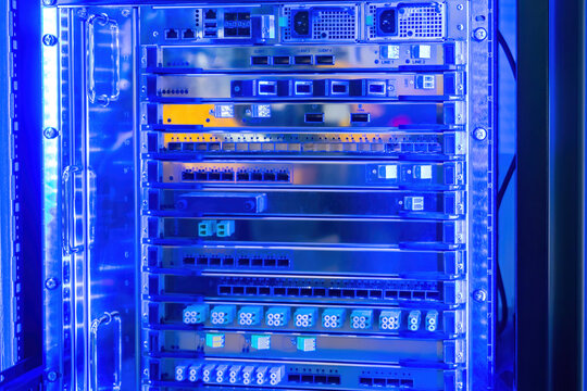 Network hardware. Dense Wavelength Division Multiplexing. Server system with transponders. Server cabinet in neon lighting. Fragment of switching equipment. Server multiplexing technology