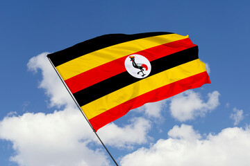 Uganda flag isolated on the blue sky background. close up waving flag of Uganda. flag symbols of Uganda. Concept of Uganda.