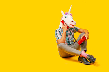 man with a unicorn mask talks on the phone