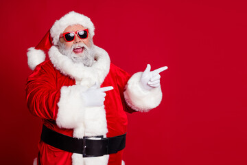 Photo of promoter pensioner funny man direct finger empty space wear santa hat costume isolated red color background
